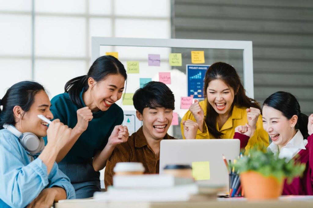 Excited team celebrating viral marketing success around laptop