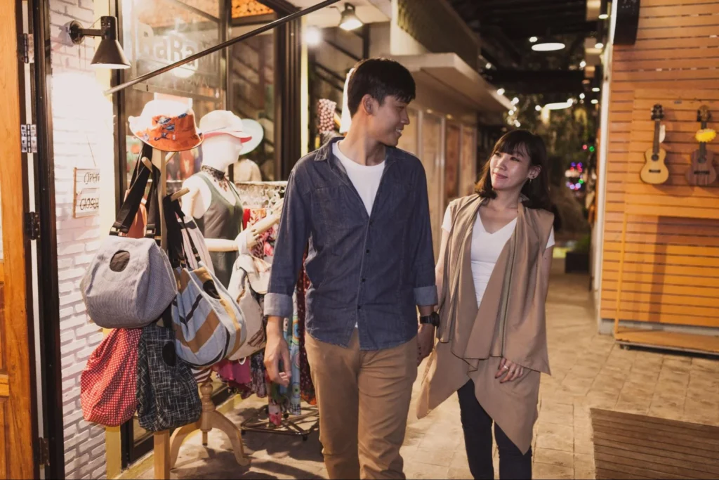 Young couple browsing a small fashion boutique at night, illustrating Gen Z interest in lifestyle retail and social shopping experiences
