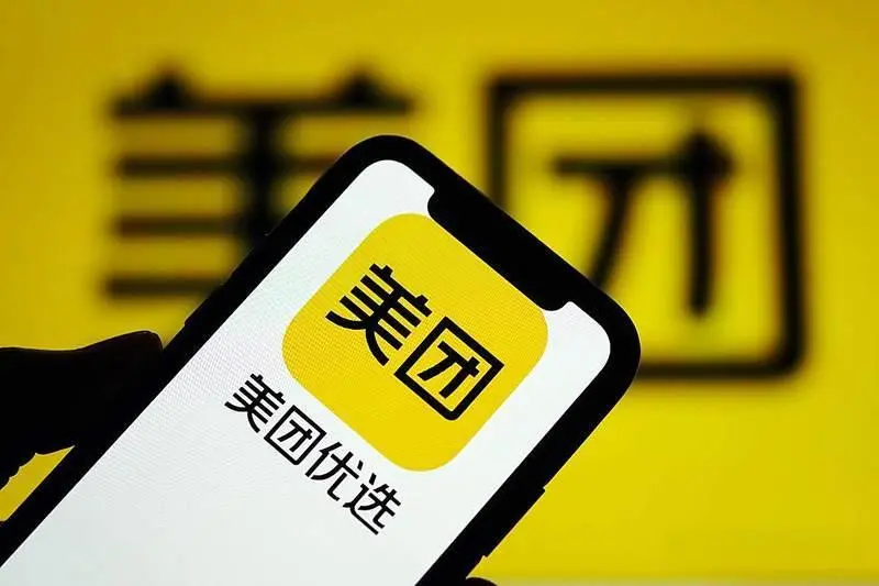 Meituan app logo on a smartphone screen against a yellow background