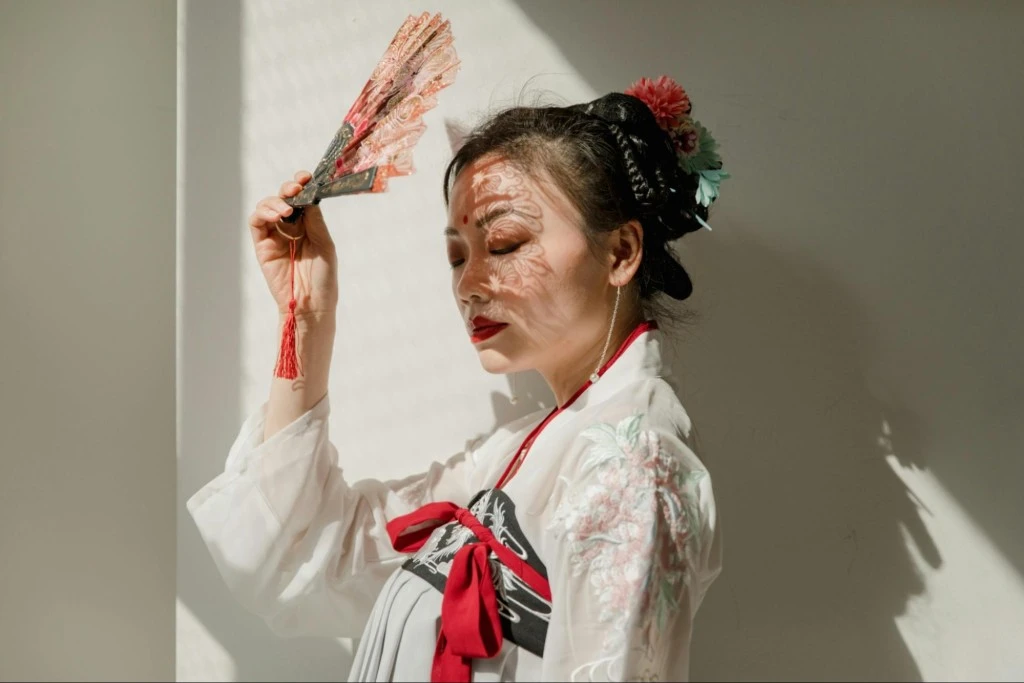Woman in traditional inspired fashion holds a decorative fan, reflecting guochao style and identity driven consumption in China.