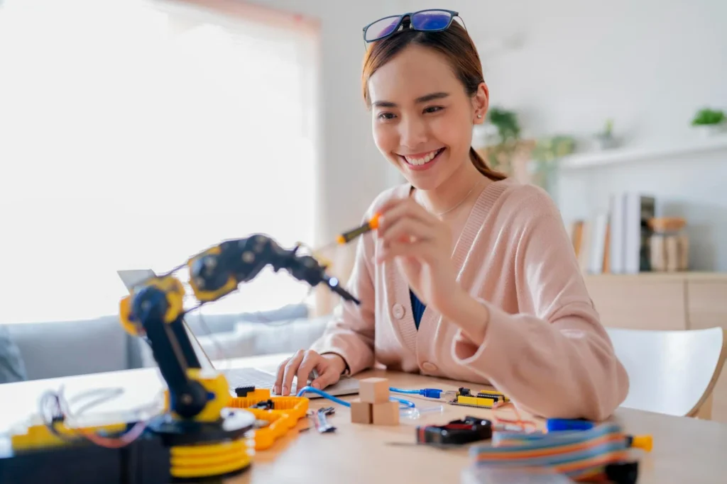 Woman assembling small robotic arm at home, highlighting consumer robotics and learning trends in Chinese AI in 2026.