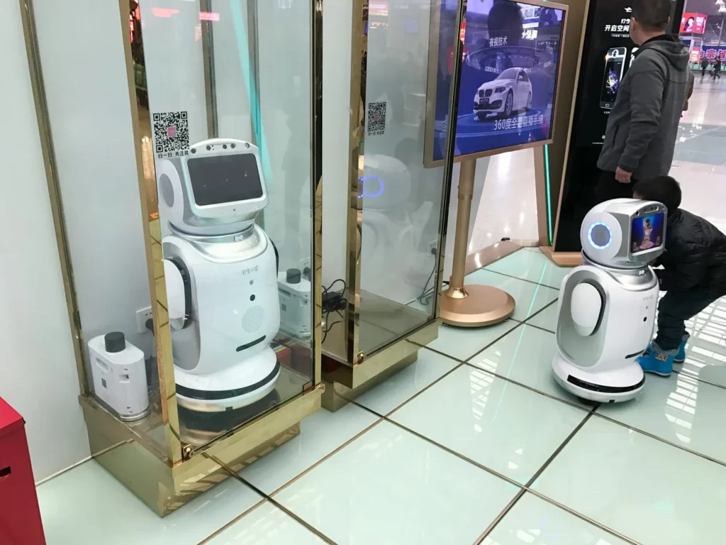 Service robots interacting with visitors inside a shopping mall, illustrating public-facing automation and Chinese AI in 2026 urban deployment.