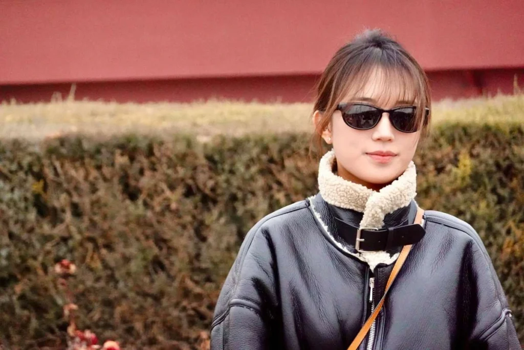 Woman wearing sunglasses and a shearling jacket outdoors, representing everyday premium style in China
