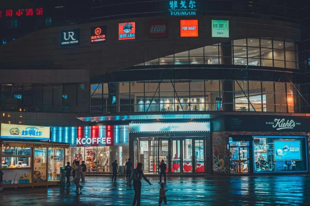 Modern retail center in China at night with branded storefronts and shoppers outside