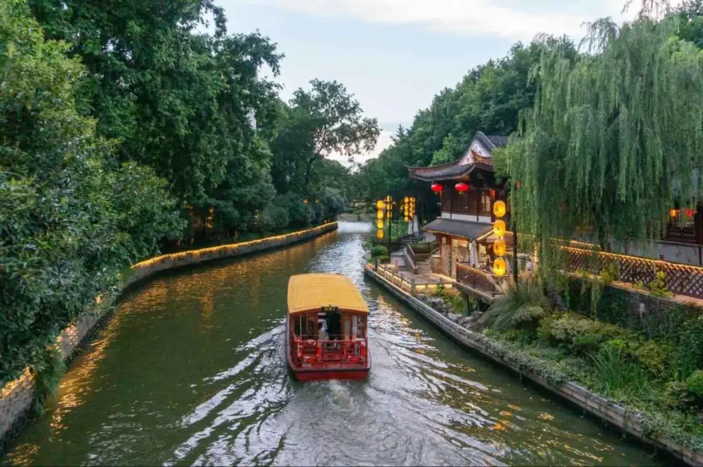 A boat moves through a quiet Chinese water town, reflecting travel as recovery for Chinese consumers.