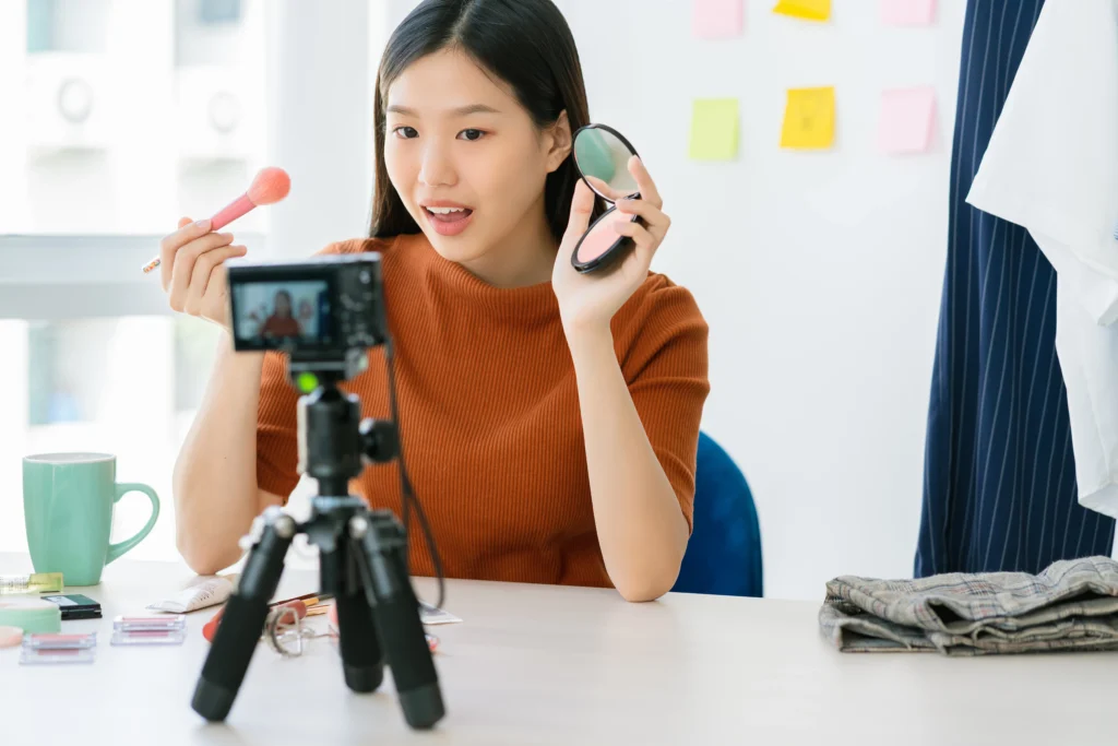 taobao live: beauty influencer demonstrating makeup during a livestream using a camera setup and cosmetics products