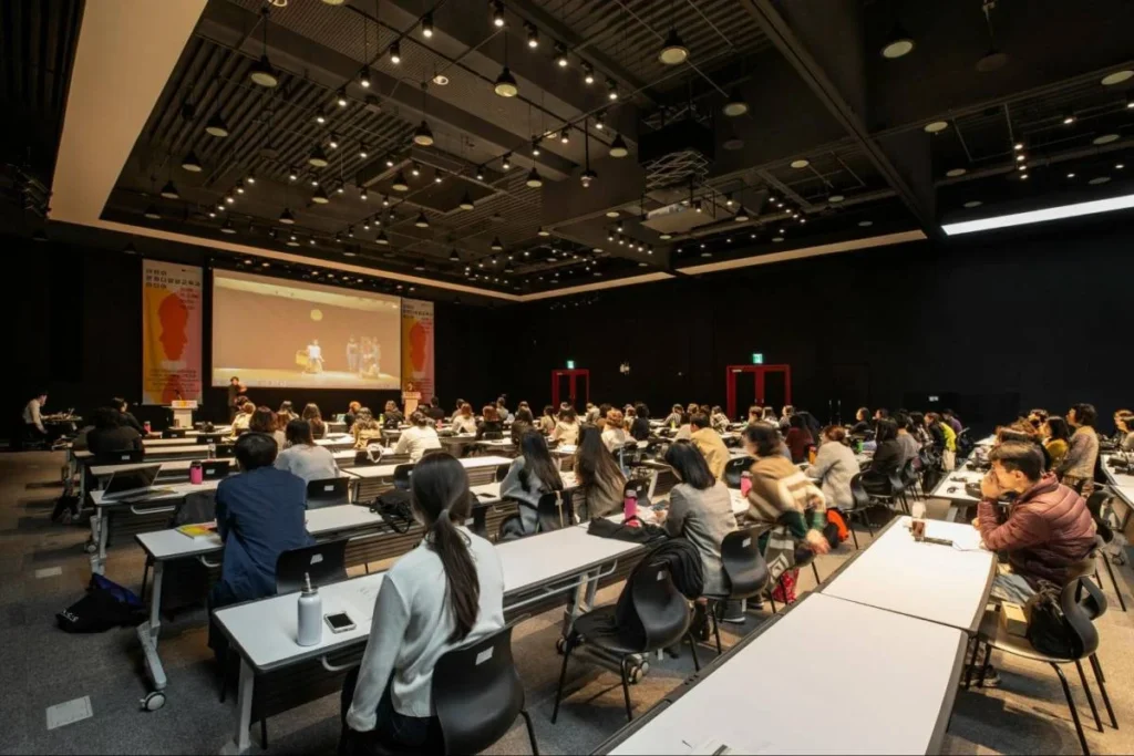 Conference audience learning from a keynote speaker in a large business event setting