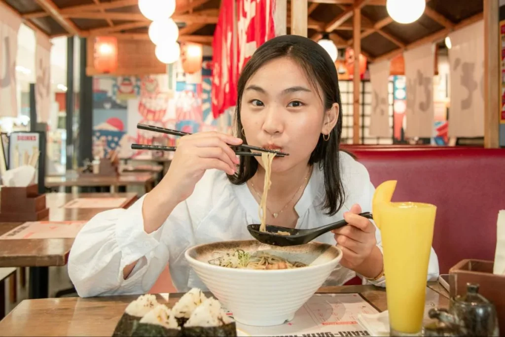 Woman dining alone in a noodle restaurant, showing how living alone influences food portions and everyday spending.
