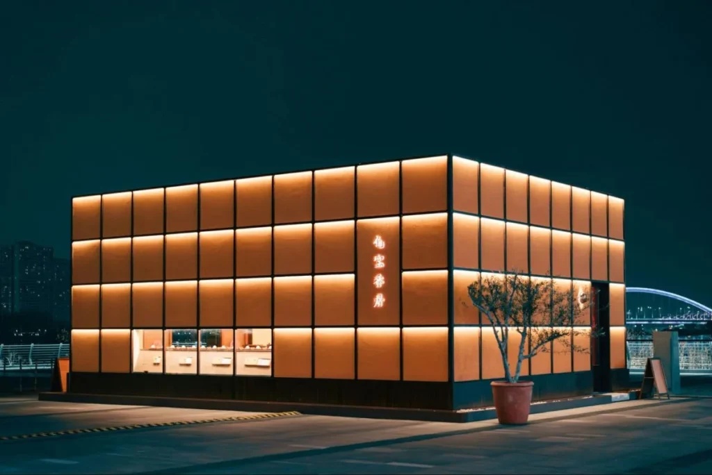 Illuminated retail storefront at night representing memorable physical touchpoints in a phygital retail journey.