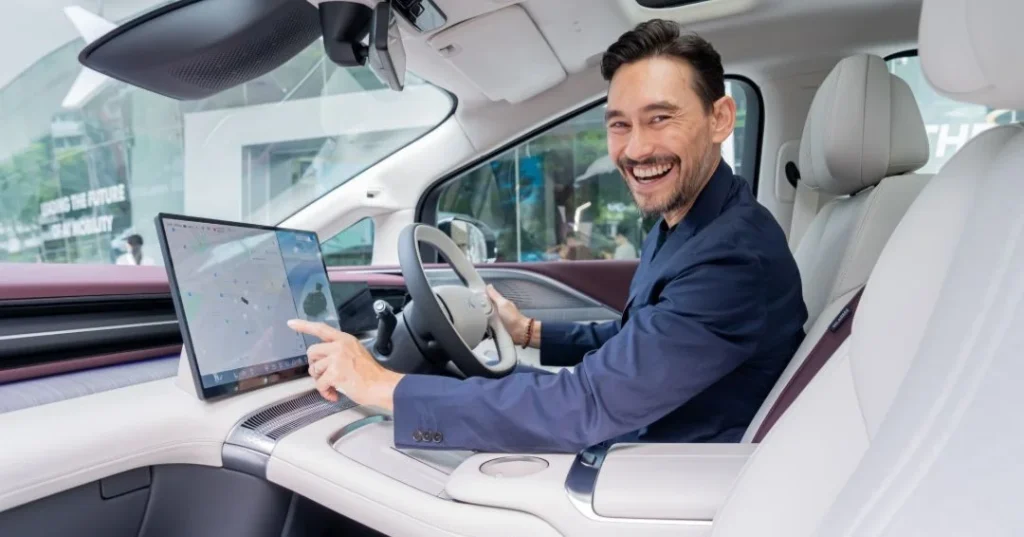 A driver demonstrates a large in-car touchscreen in a Chinese EV cabin.