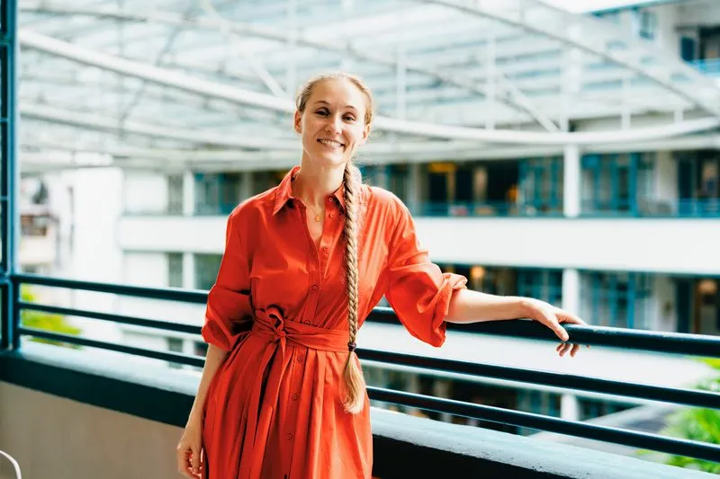 Woman in orange dress standing inside a modern shopping mall