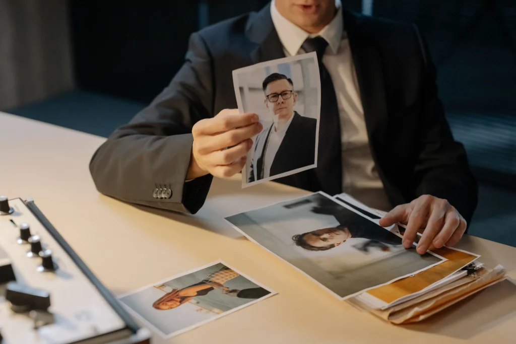 Businessperson reviewing printed portrait photos as possible evidence
