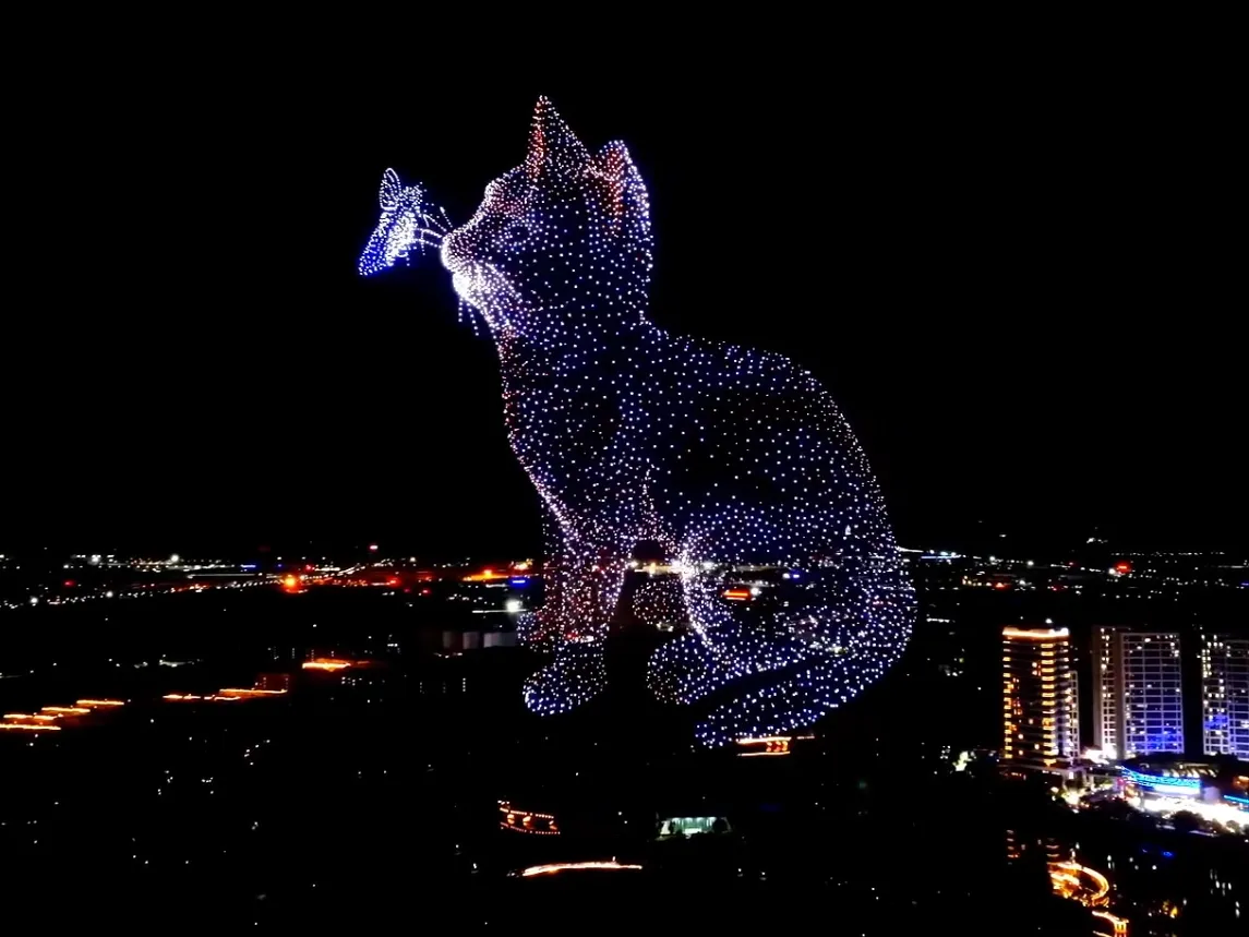 Drone light show forming a giant cat above a city skyline