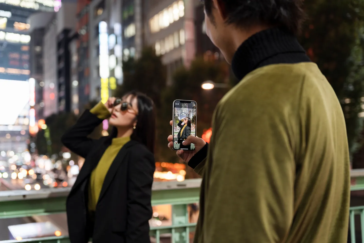 Person taking a smartphone photo of a woman in a city