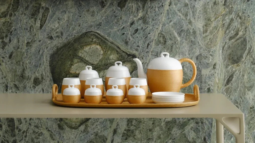 White and woven tea set arranged on a tray against a stone wall.
