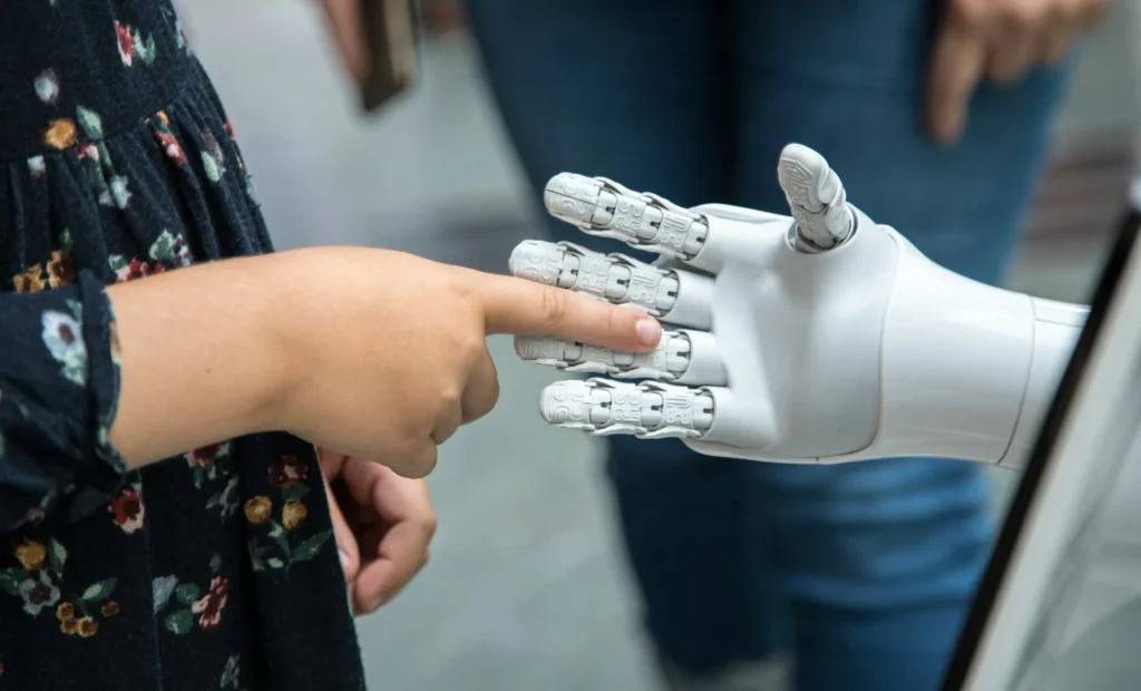 Child touching a white robotic hand during a technology demonstration
