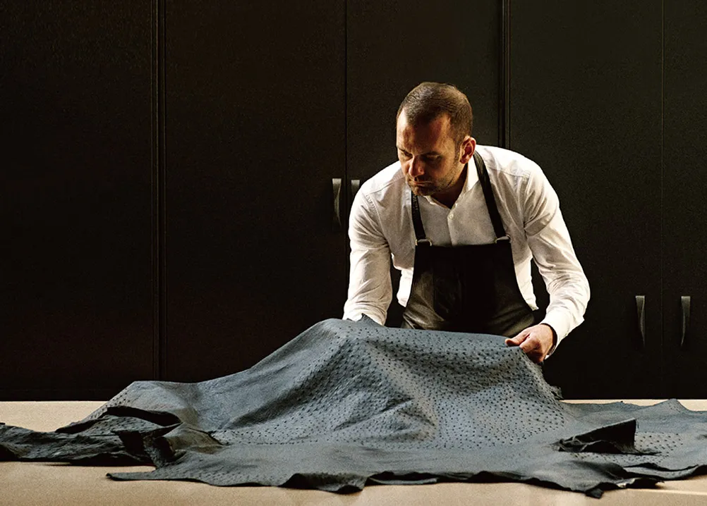 Artisan inspecting textured leather for DISSONA bag production