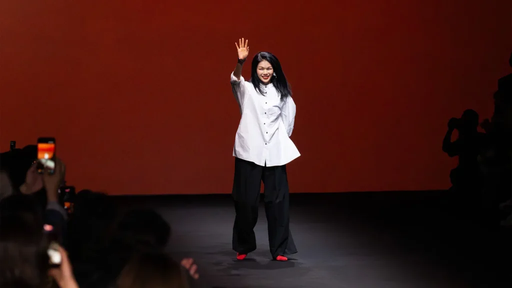 Designer waving on fashion runway stage