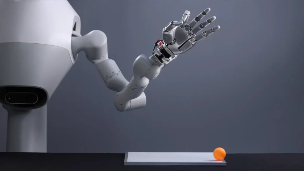 Robotic arm with open hand moving near an orange ball