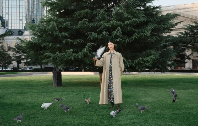 Model wearing JNBY coat in a green city park