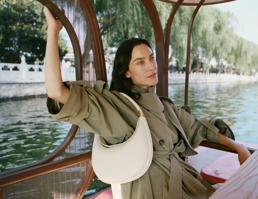 Model wearing a white shoulder bag on a boat