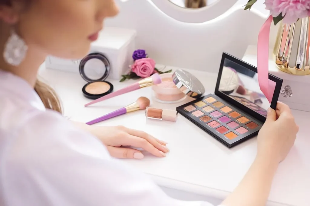 Woman using an eyeshadow palette at a beauty vanity