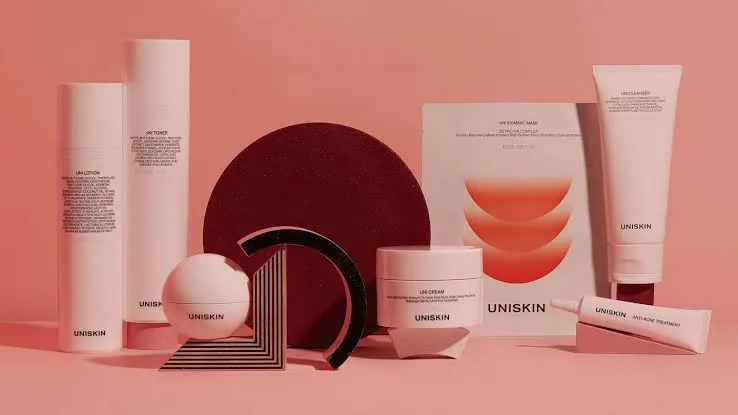 UNISKIN skin care products arranged on a coral background